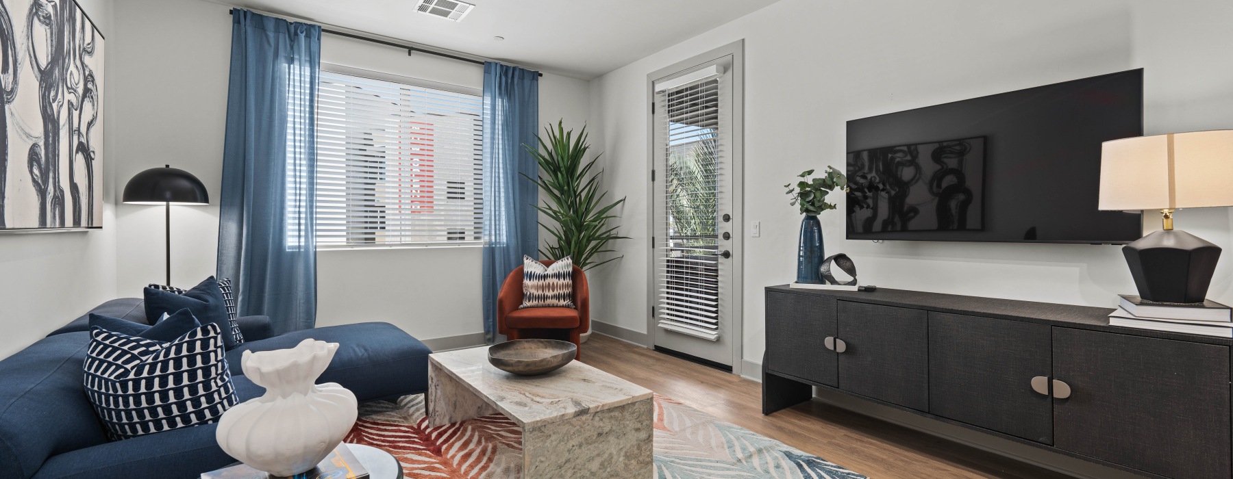 Interior living room, furnished model, large window, door leading to patio/balcony