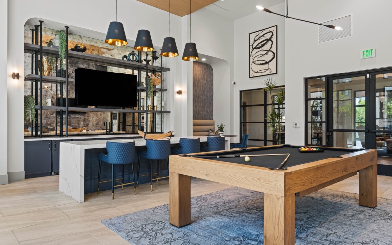 Interior clubhouse space, hardwood flooring, ceiling lighting, pool table, mounted tv, Barstool chairs 